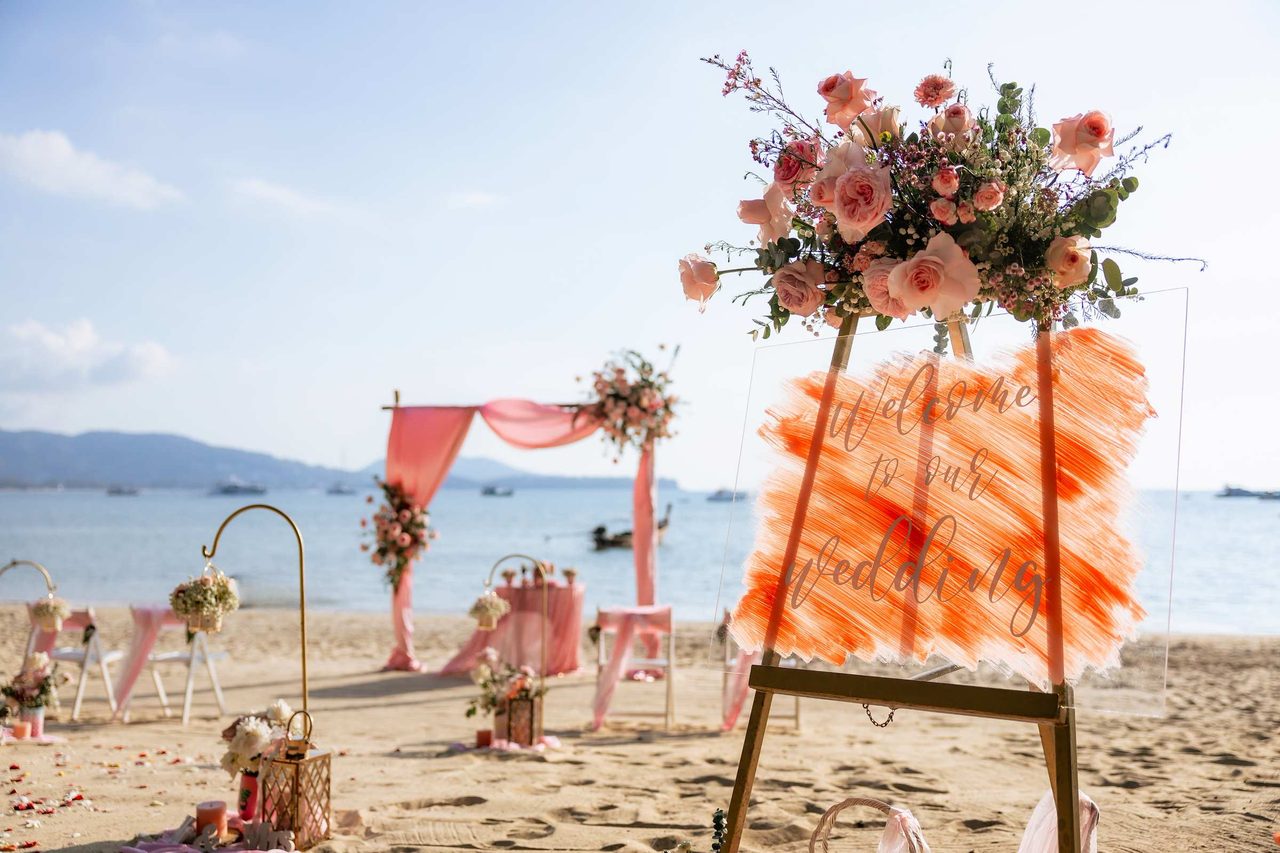 Coral and ivory floral ceremony setting on Layan Beach at sunset, designed by Wedding Flowers Phuket