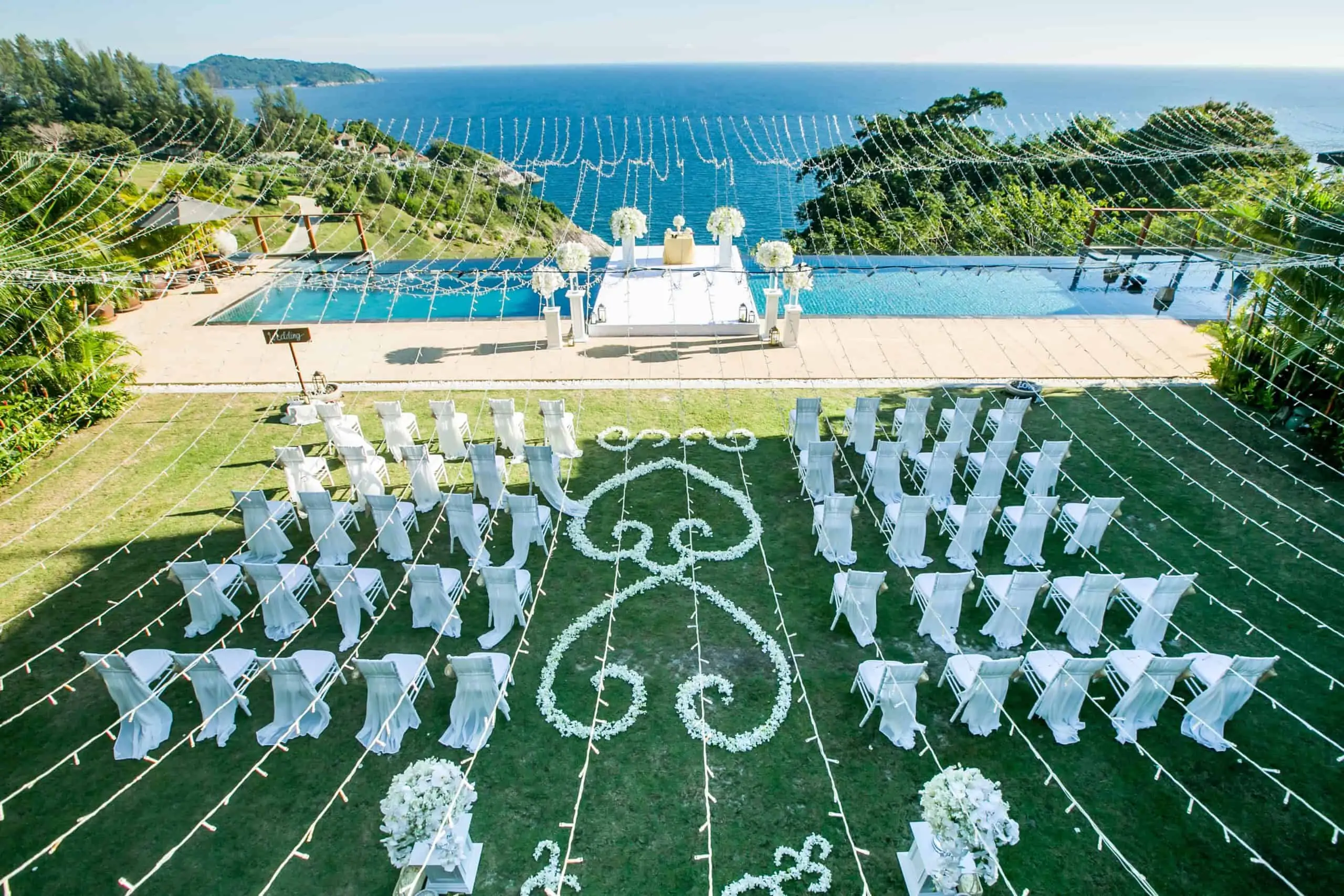 Wide luxury beach ceremony with white orchid arch and pedestals in Phuket by Wedding Flowers Phuket